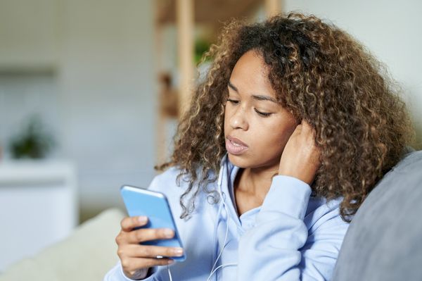 Mulher apreensiva, olhando para o celular que está na mão