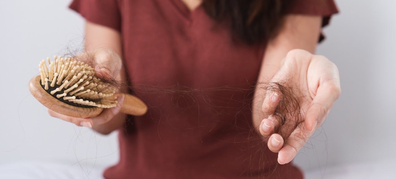 mulher com escova e tufo de cabelo nas mãos