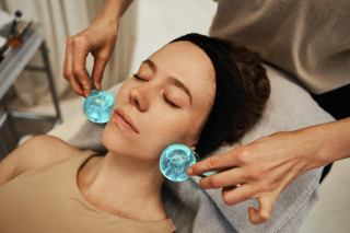 Mulher deitada em maca recebendo uma massagem com ice globes