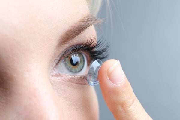 mulher colocando lentes de contato nos olhos