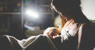 Mulher amamentando bebê durante a noite sob a luz do abajur