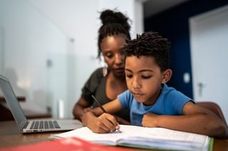 Criança estudando com o auxílio da mãe