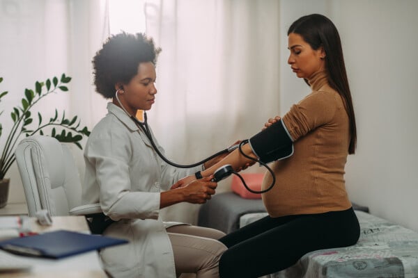 Mulher gravida tendo a sua pressão arterial aferida por uma médica