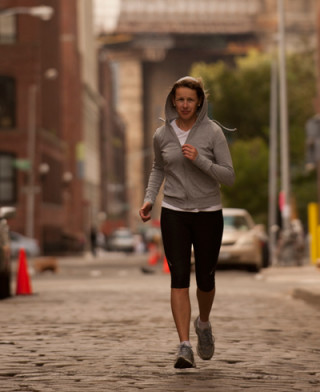 mulher correndo em uma rua de paralelepípedos - Foto Getty Images