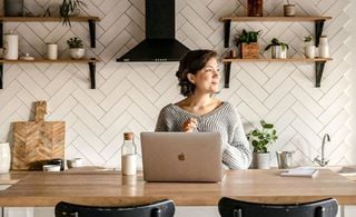 Mulher em uma cozinha com um notebook sobre uma bancada