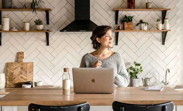 Mulher em uma cozinha com um notebook sobre uma bancada