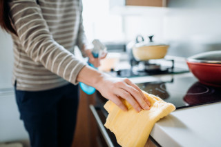 Mulher limpando fogão com pano amarelo