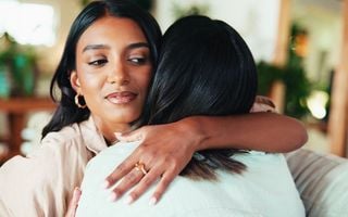 mulher abraçando uma amiga com cara de desconfiança