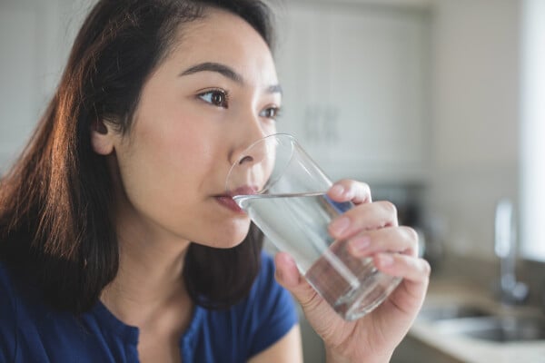 Mulher bebendo água para combater o soluço