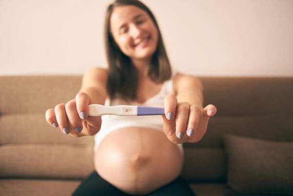 Mulher grávida desfocada segurando um teste de gravidez positivo