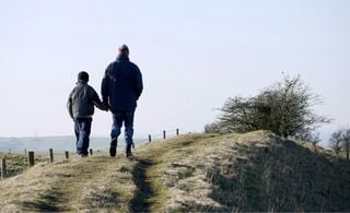 Adulto e criança de costas caminhando em uma trilha