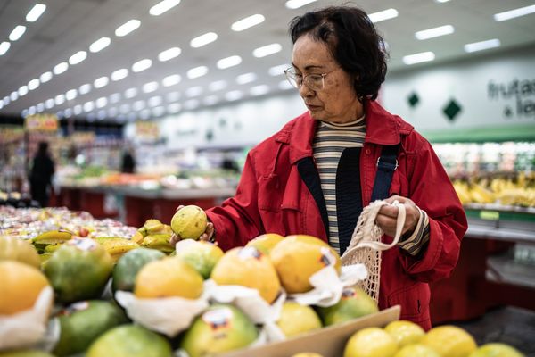 mulher idosa escolhendo goiaba no supermercado