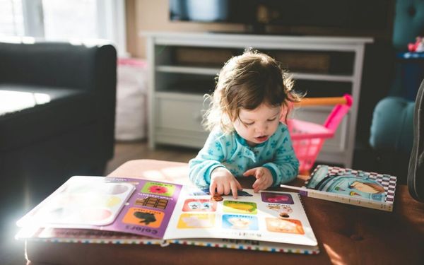 criança lendo livro em uma mesa