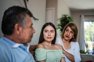 Pai, mãe e filha juntos em um sofá