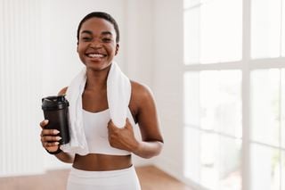 Mulher com um copo de pré-treino na mão