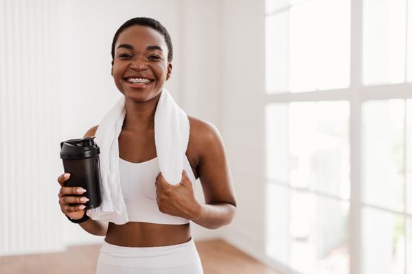 Mulher com um copo de pré-treino na mão