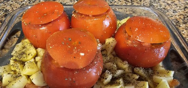 Tomates recheados em uma travessa com batatas com orégano