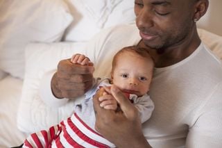 Pai negro com tom de pele escuro segurando seu bebê de pele clara
