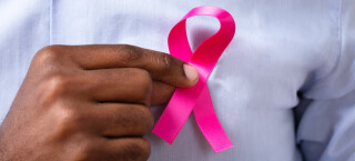 Homem segura laço que representa outubro rosa, a campanha contra o câncer de mama