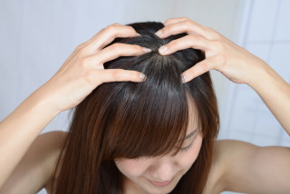Mulher massageando o próprio couro cabeludo