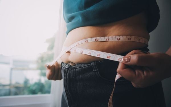 mulher medindo a barriga com uma fita métrica
