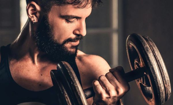 Homem olhando os músculos enquanto levanta um halter