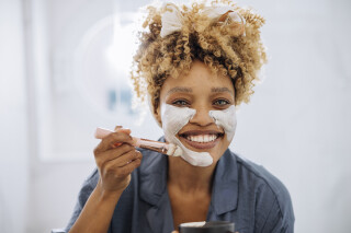 Mulher na frente do espelho aplicando máscara facial de peptídeos