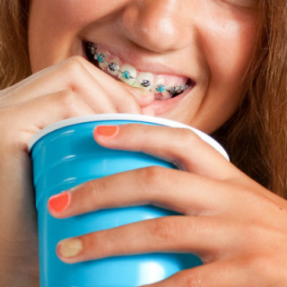Menina de aparelho tomando refrigerante - Foto: Getty Images