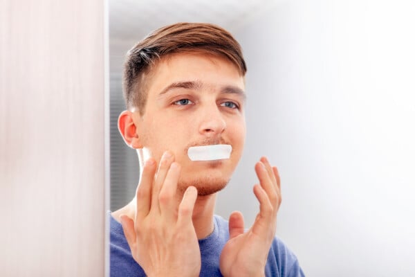 Homem com a boca tapada com um adesivo se olhando no espelho