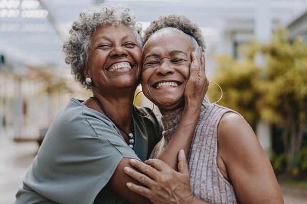 Duas mulheres negras se abraçando e sorrindo