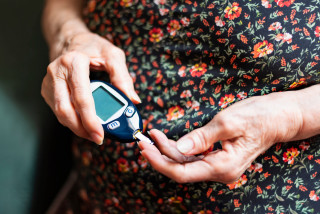 Mulher mais velha medindo a glicose com aparelho no dedo