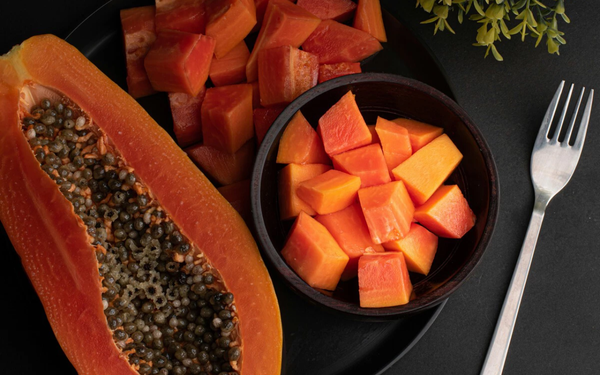 Banda de mamão papaya ao lado de tigela com mamão em cubos