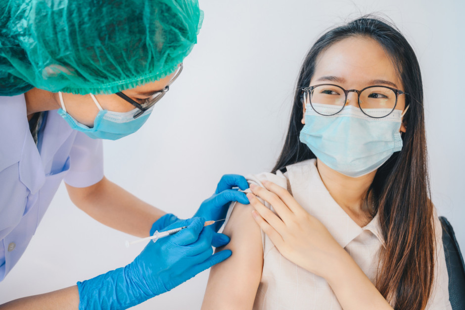Enfermeira aplicando vacina no braço de adolescente