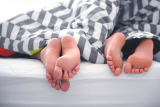 Casal com pés descobertos na cama