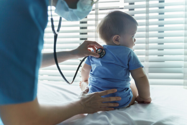Médica pediatra examinando um bebê paciente com estetoscópio na sala médica