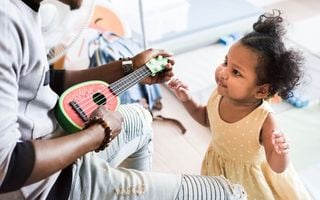 pai tocando violão pra filha pequena