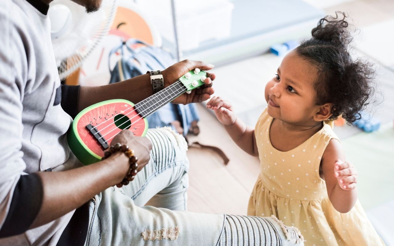 pai tocando violão pra filha pequena