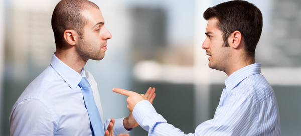 Dois homens de camisa e gravata conversam de modo provocativo