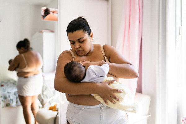 mulher em pé amamentando bebê em casa