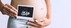 Imagem de uma mulher grávida segurando uma imagem de ultrassom