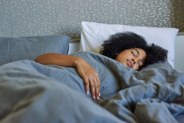 mulher com cabelos cacheados dormindo em uma cama
