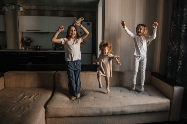 Três crianças pulando em sofá