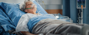 Mulher idosa deitada em cama de hospital na UTI usando uma máscara de oxigênio