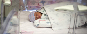 Bebê prematuro dormindo dentro de incubadora em hospital neonatal