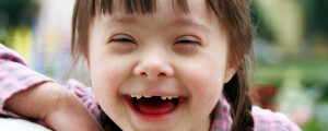 Garota de cinco anos com síndrome de Down sorrindo para a foto