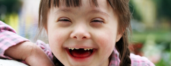 Garota de cinco anos com síndrome de Down sorrindo para a foto