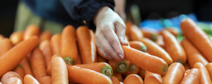 Mulher pegando cenoura em mercado