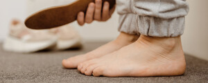 Imagem ampliada de um pé com diagnóstico de pé chato, ao lado de uma mão segurando uma palmilha