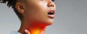 Mulher negra com semblante de dor e a mão direita sobre a garganta, sinalizada com uma luz vermelha