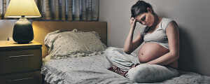 adolescente grávida com depressão sentada na cama com uma mão na teste